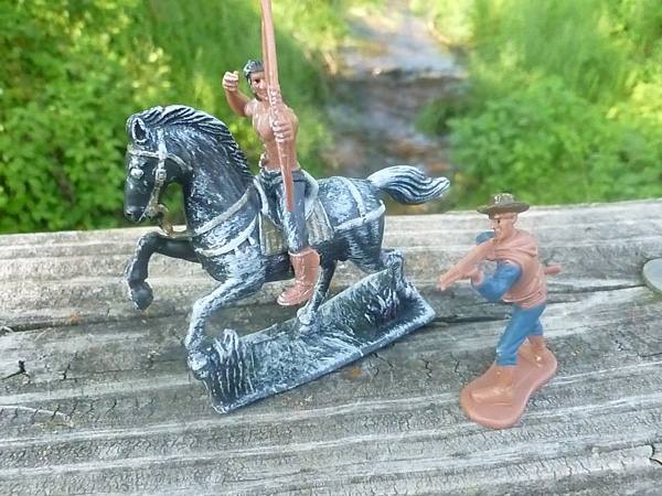 Cowboy and Indian toys posed outdoors